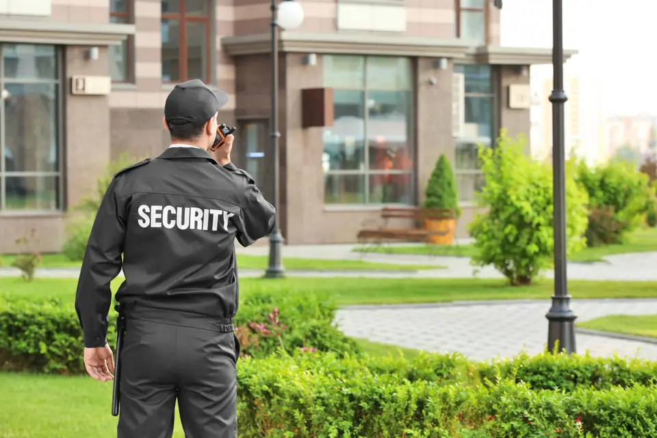 Sicherheitsmitarbeiter mit Funkgerät vor einem Gebäude